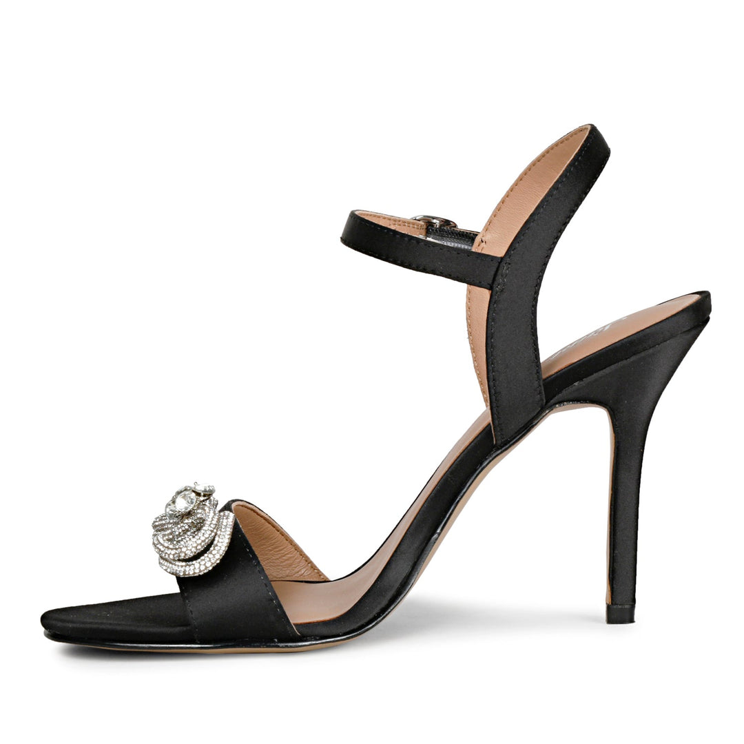 Black leather-satin stilettos by Saint Hayden, adorned with a crystal bow for a chic and stylish vibe.